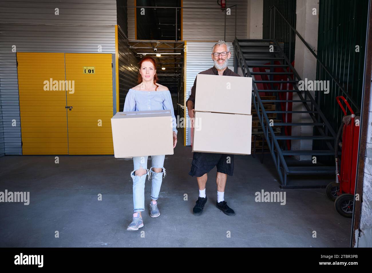Ein Mann und eine Frau tragen Pappkartons mit Sachen Stockfoto