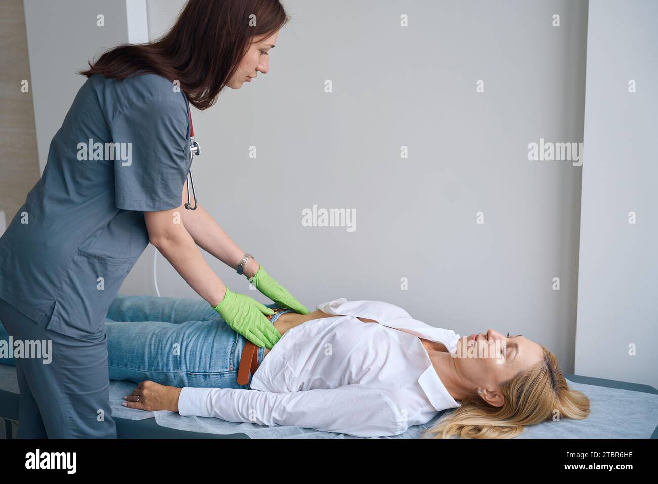 Hausarzt, der die Abdominaluntersuchung der Reifen Frau durchführt Stockfoto