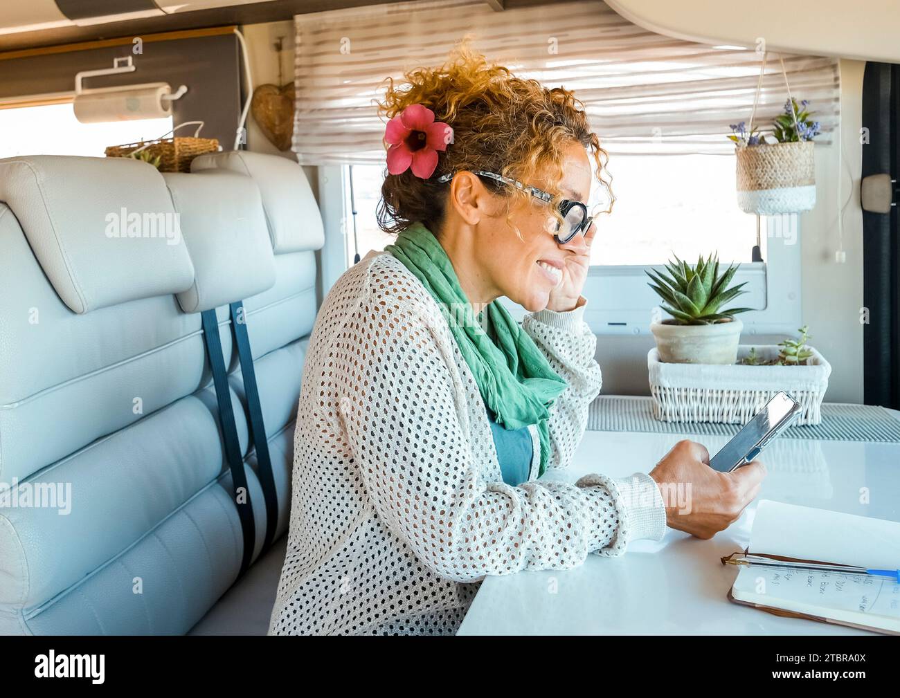 Eine Alleinreisende genießt Zeit und Freizeitaktivitäten in einem modernen Wohnmobil mit einem Mobiltelefon und drahtloser Roaming-Verbindung. Moderne Menschen und Technik im Reisekonzept Stockfoto