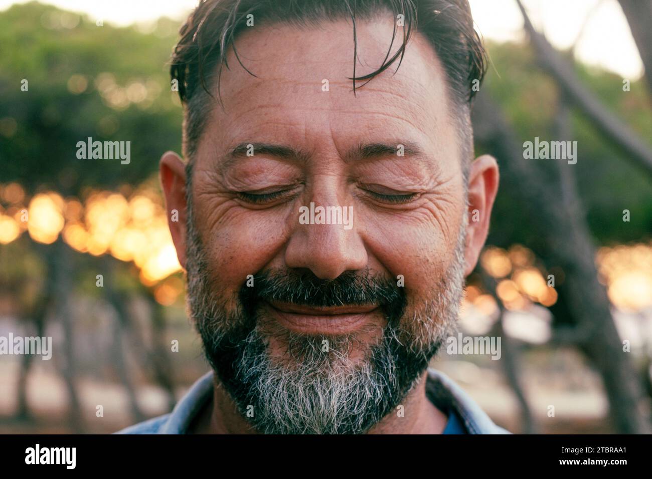 Nahaufnahme des Porträts eines Reifen Mannes mit Bart und geschlossenen Augen, der vor der Kamera lächelt. Wohlbefinden und psychische Gesundheit Konzept Glück Lebensstil. Innenraumlebensbalancierung positiv. Erwachsene männliche Menschen in Outdoor-Freude Stockfoto