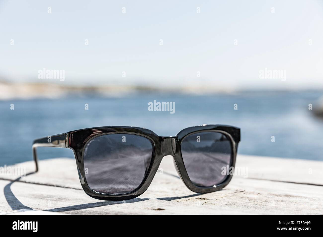 Sonnenbrille auf einer Holzterrasse am Strand Stockfoto