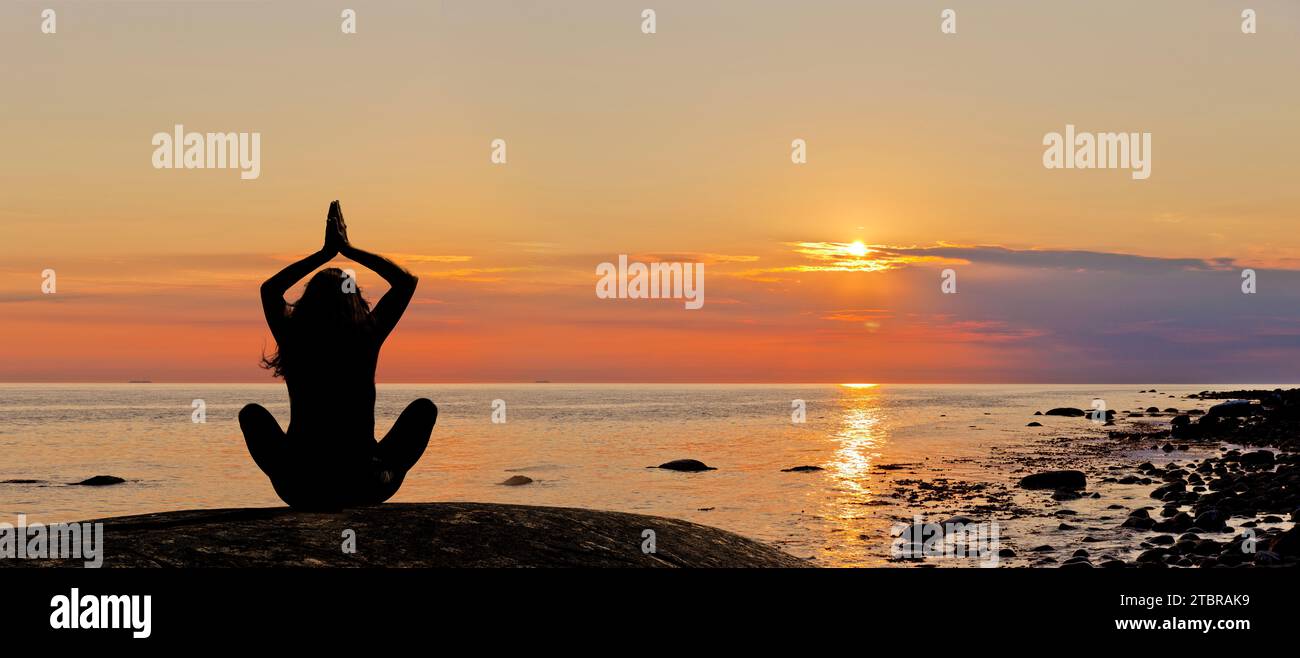 Frau, die Yoga bei Sonnenuntergang am Strand feiert Stockfoto