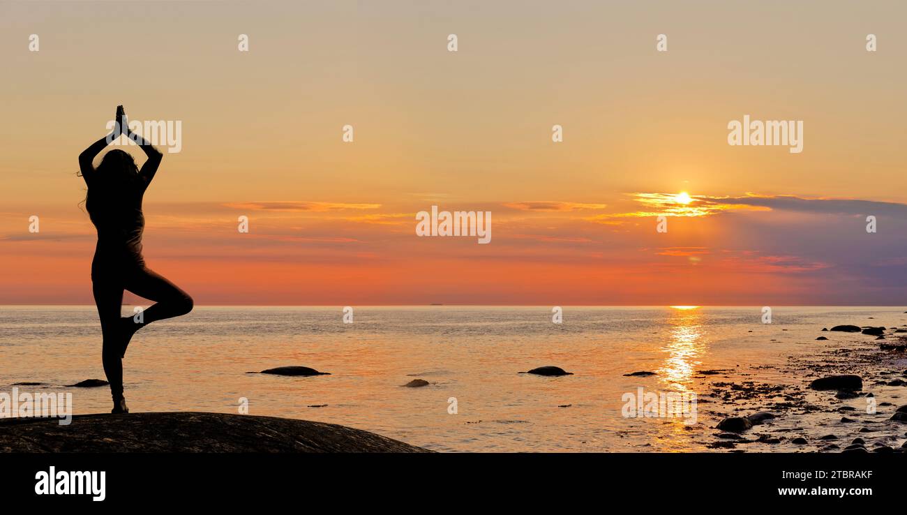 Frau, die Yoga bei Sonnenuntergang am Strand feiert Stockfoto