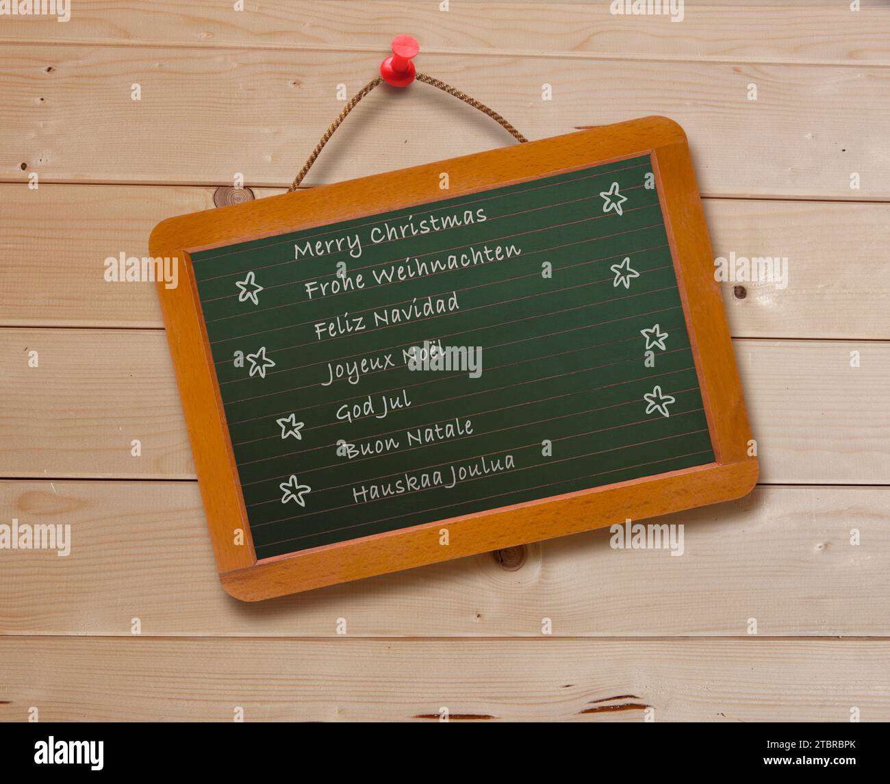 Weihnachtswünsche in verschiedenen Sprachen auf einem Brett Stockfoto