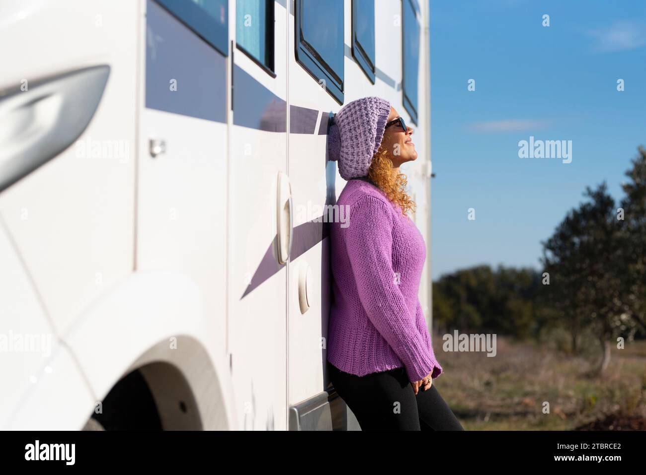 Eine glückliche Touristikerin steht und entspannt sich vor ihrem modernen Wohnmobil-Wohnmobil und genießt Outdoor-Freizeitaktivitäten allein. Vanlfe. Reiseurlaubsfrauen allein draußen Stockfoto