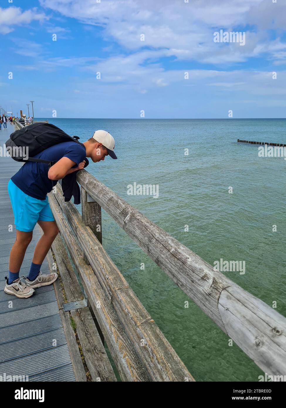 Deutschland, Mecklenburg-Vorpommern, Halbinsel Fischland-Darß-Zingst, ein Teenager blickt über das Geländer der Pier Zingst ins Meerwasser Stockfoto