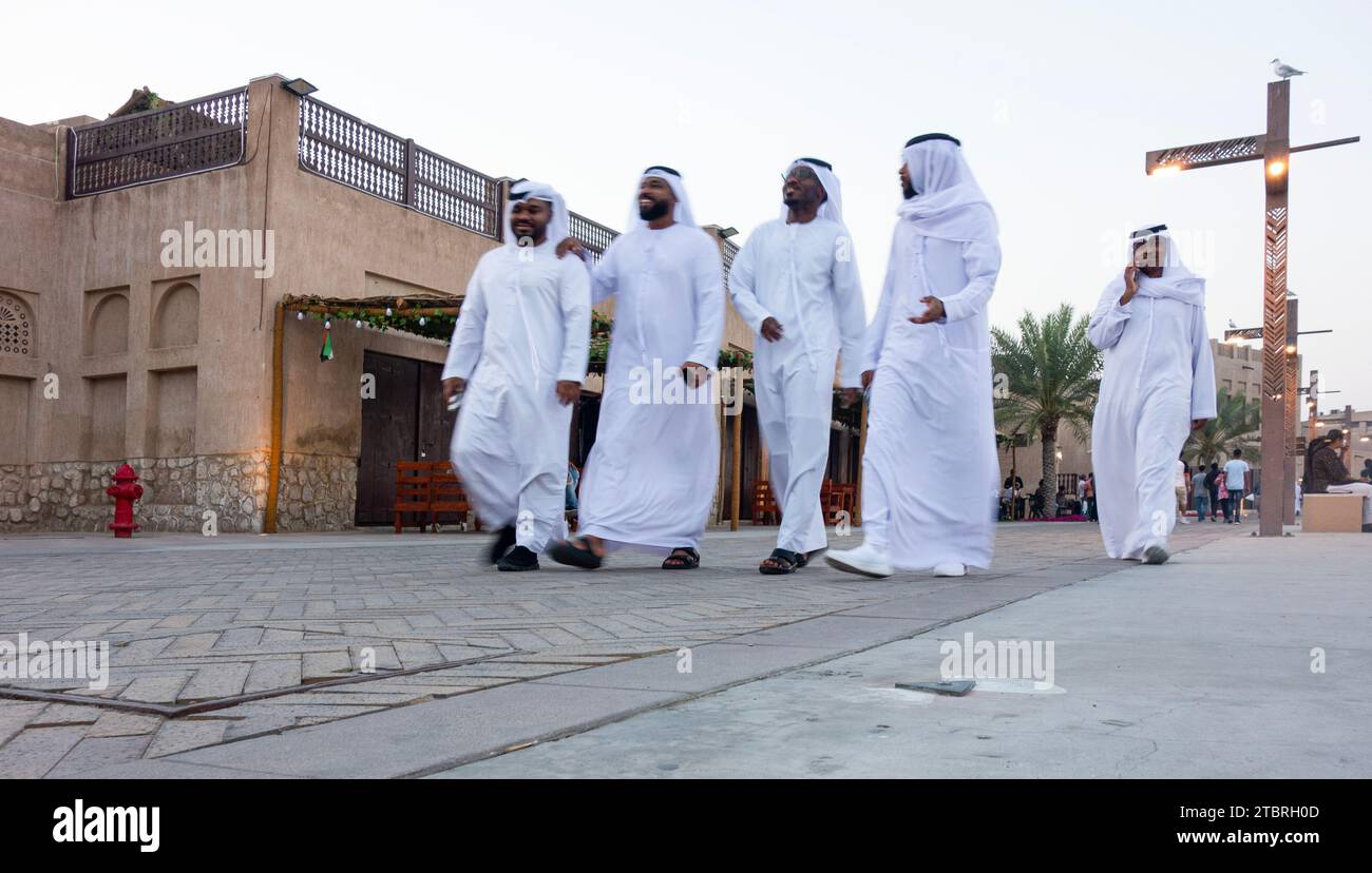 Eine kleine Gruppe von Emiraten spaziert durch das Al Shindagha Heritage District in der Abenddämmerung, Dubai, VAE. Stockfoto