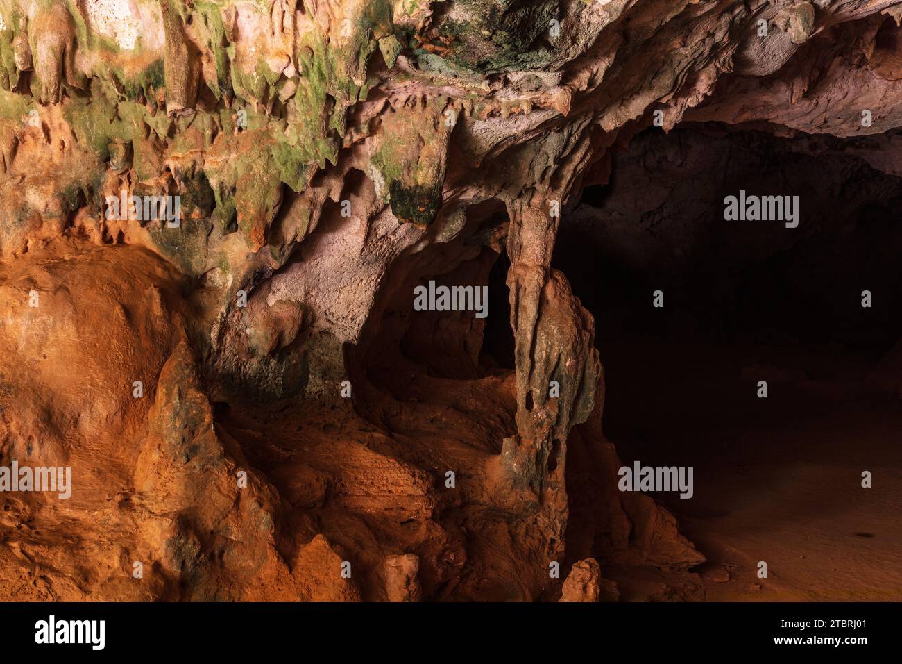 Mehrfarbige Steinsäulen in der Quadiriki-Höhle im Arikok-Nationalpark, Aruba. Farbige Steinwände und -Decke; offene Höhle im Hintergrund. Stockfoto