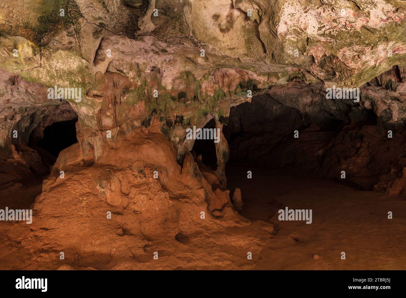 Mehrfarbige Steinsäulen in der Quadiriki-Höhle im Arikok-Nationalpark, Aruba. Farbige Steinwände und -Decke; offene Höhle im Hintergrund. Stockfoto