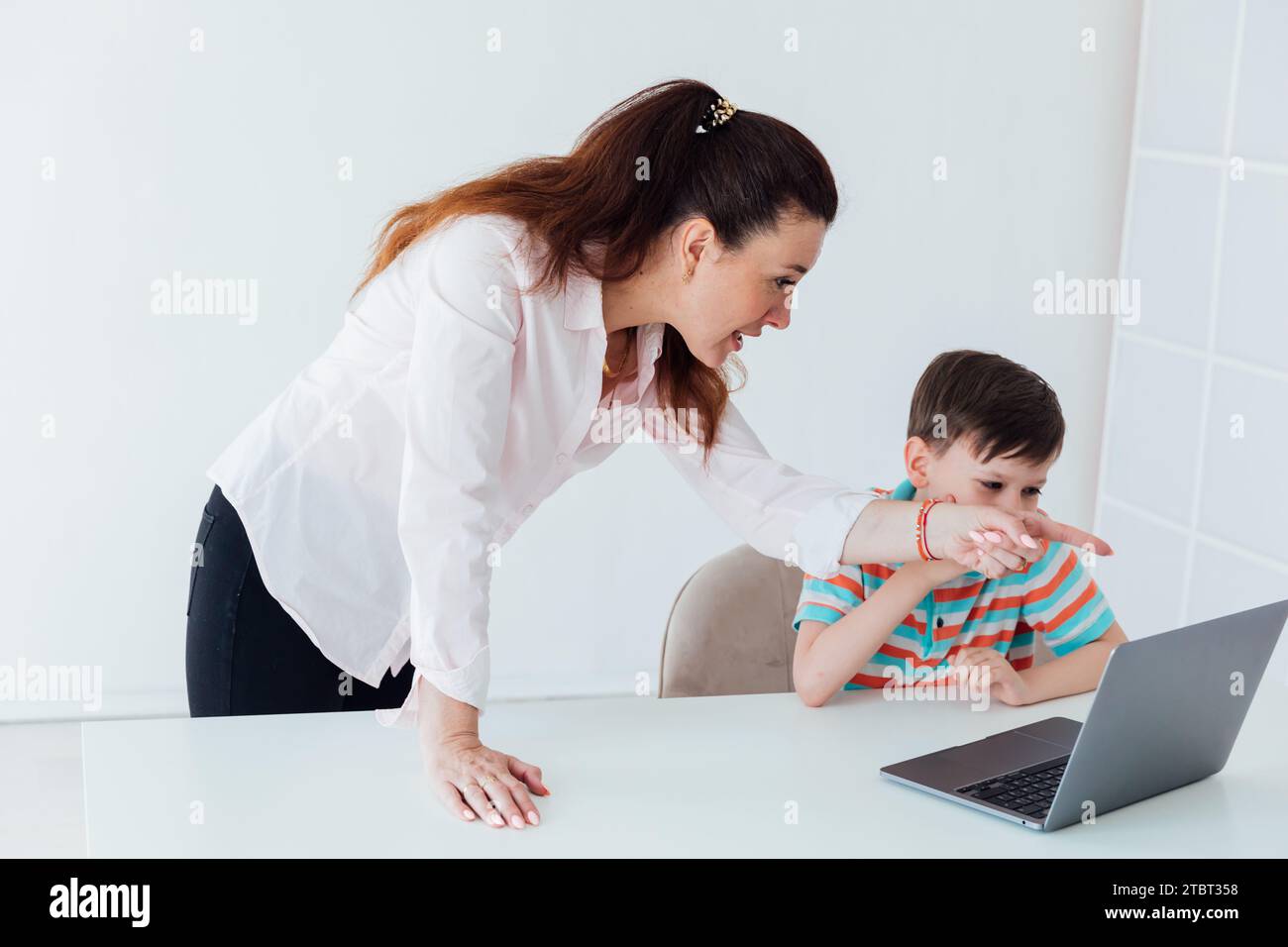 Die Frau bringt dem Jungen bei, online am Computer zu arbeiten Stockfoto