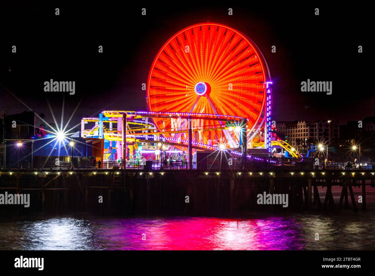 Pacific Park am Santa Monica Pier, Santa Monica, Kalifornien, mit dem Riesenrad und der Achterbahn, die bei Nacht im Ozean reflektiert wird Stockfoto