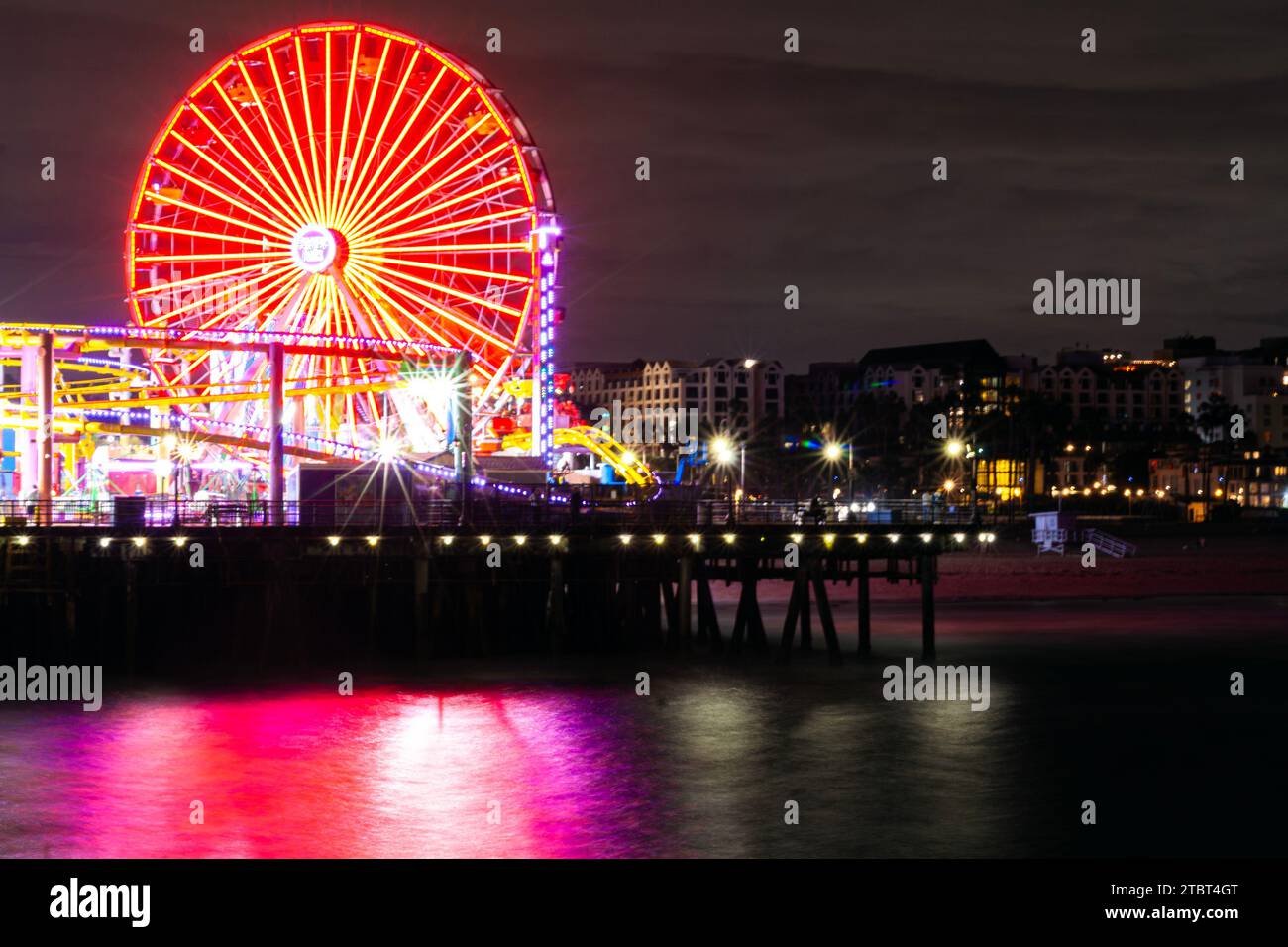 Pacific Park am Santa Monica Pier, Santa Monica, Kalifornien, mit dem Riesenrad und der Achterbahn, die bei Nacht im Ozean reflektiert wird Stockfoto