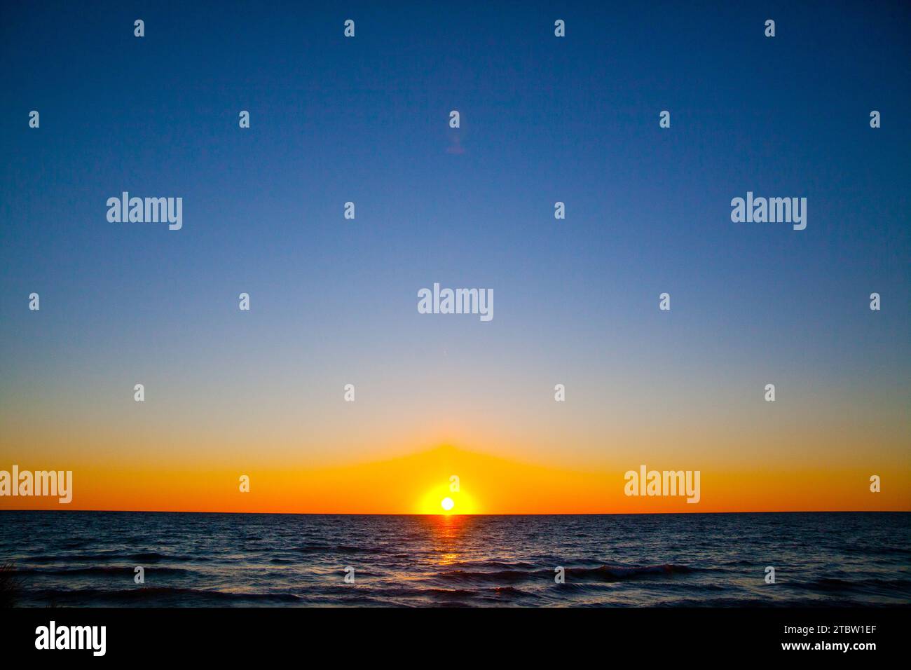 Goldener Sonnenuntergang über Lake Michigan mit ruhigen Meereswellen Stockfoto