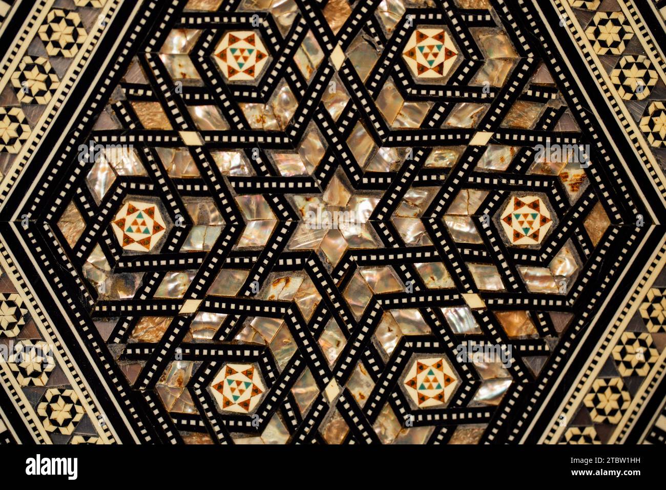 Sechseckiges Kastendesign mit marokkanischem Einlegedesign im Mittleren Osten auf gemustertem Teppich Stockfoto