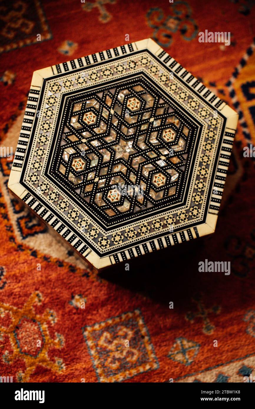 Sechseckiges Kastendesign mit marokkanischem Einlegedesign im Mittleren Osten auf gemustertem Teppich Stockfoto