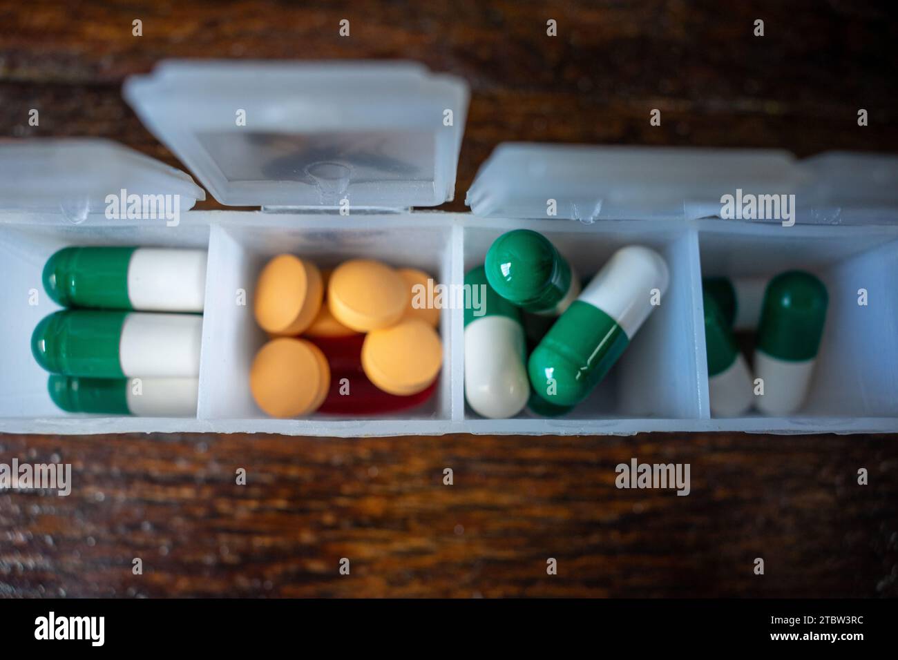 Pillen-Organizer-Box, mit orangefarbenen und grünen Pillen Stockfoto