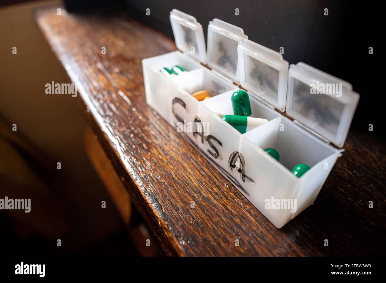 Pillen-Organizer-Box, mit orangefarbenen und grünen Pillen Stockfoto