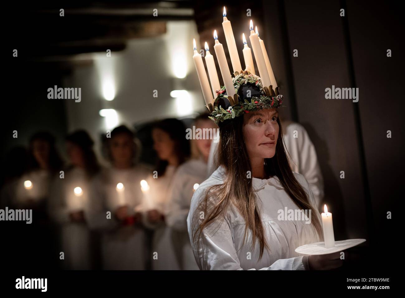 London, Großbritannien. Dezember 2023. Sankta-Lucia-Feiern des schwedischen Chors Norrsång East London in der St. Mary’s Church in Walthamstow. Isabelle Wasmuth Dunnett trägt eine Kerzenkrone, die die hl. Lucy symbolisiert, während sie die Sankta Lucia feiert, basierend auf der Tapferkeit und dem Martyrium eines jungen sizilianischen Mädchens St. Lucy (Lucia von Syrakus 283–304). Guy Corbishley/Alamy Live News Stockfoto