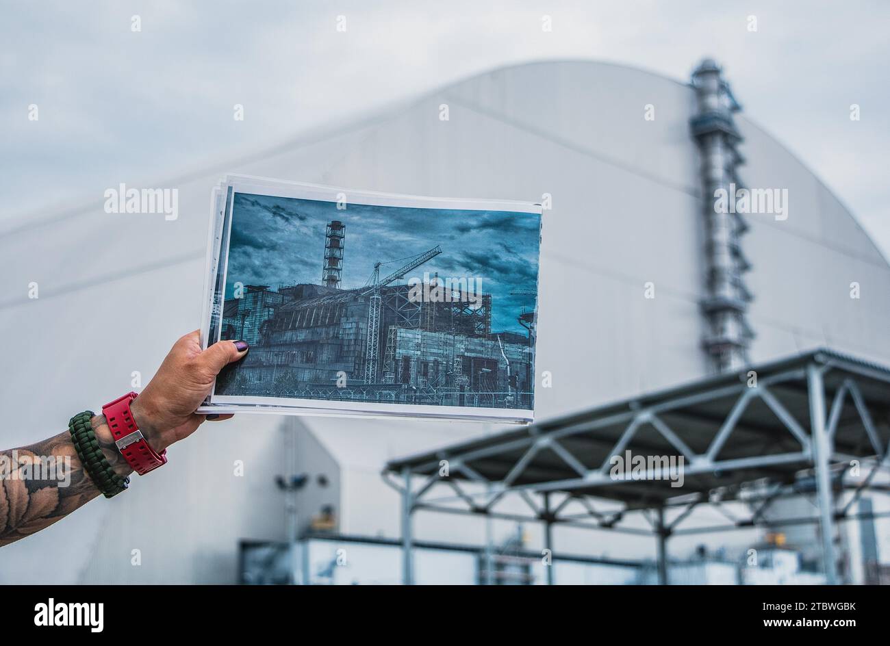 Ein Bild von jemandem, der ein Bild des alten Sarkophags zeigt, der den vierten Reaktor des Kernkraftwerks Tschernobyl vor dem schützte Stockfoto