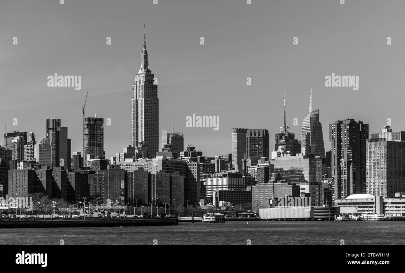 Ein Schwarzweiß-Bild des Empire State Building, das über den nahe gelegenen Gebäuden von Manhattan thront Stockfoto