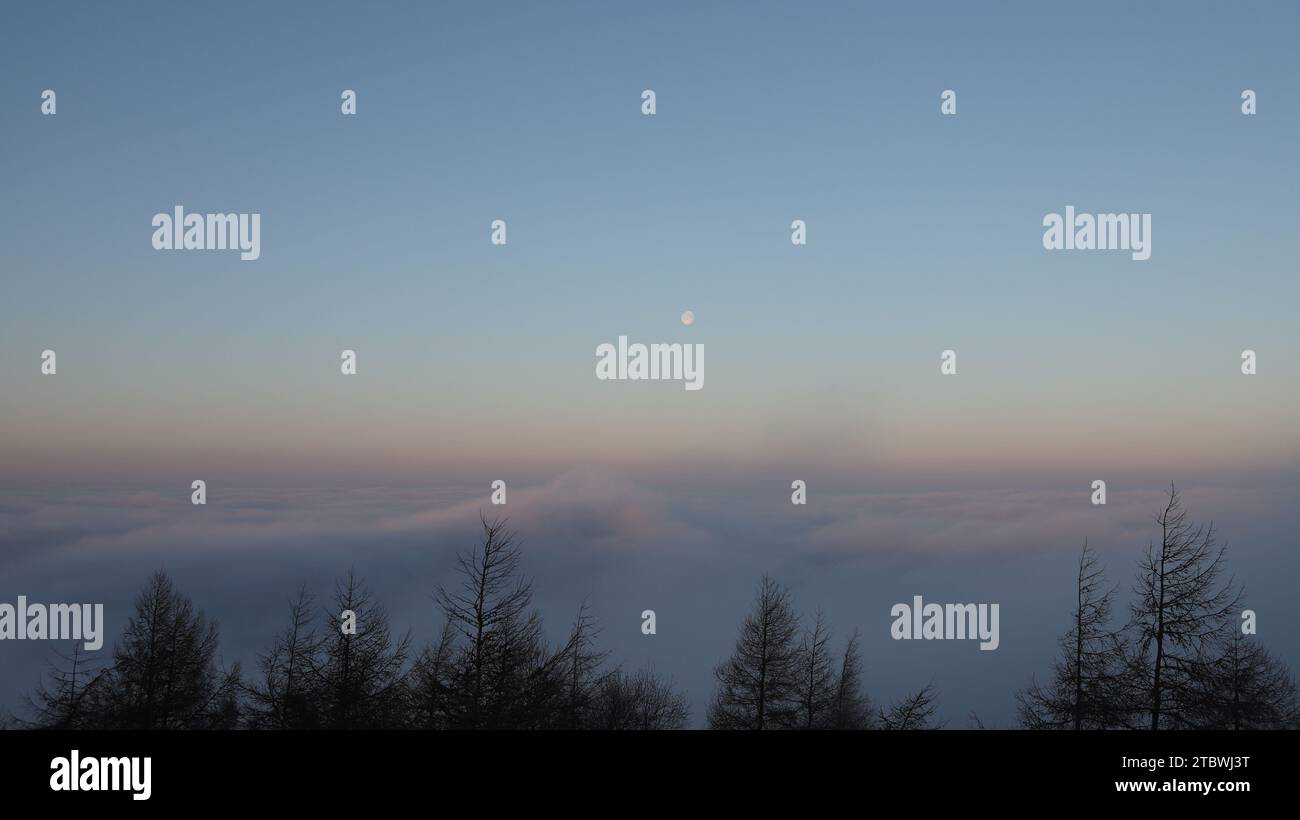 In Wolken liegt die geschäftige Stadt Accrington unter einer Decke aus stratuswolke, während der Mond allein steht und bei klarem Himmel auf so vielen Ebenen nachhallt. Stockfoto