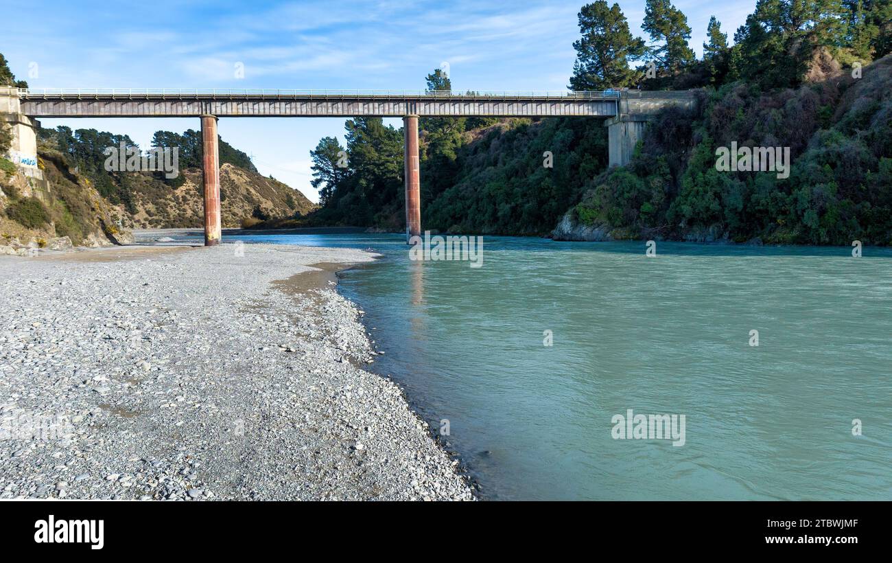 Das hellblaue, durchsichtige Wasser im Waimakariri River fließt durch die ländliche Schlucht auf landwirtschaftlichem Ackerland in der Region Canterbury in New Stockfoto