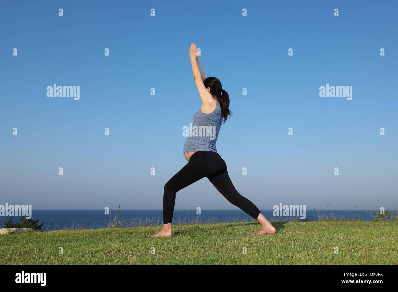 Schwangere Frau, die Yoga-Posen für Meditation am Strand macht Stockfoto