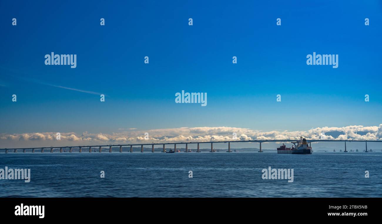 Die Niteroi-Brücke dominiert die Szene über Containerschiffen Stockfoto
