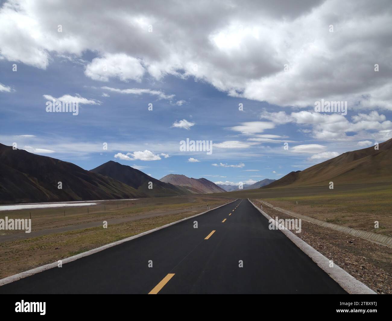 Eine unberührte zweispurige Straße, die sich durch eine bergige Landschaft schlängelt Stockfoto