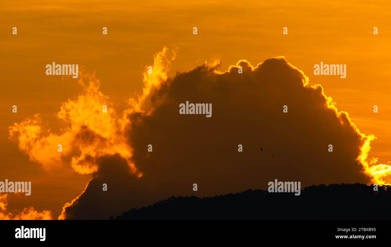 Nahaufnahme der hellen, großen Sonne am Himmel mit orangefarbenen Farbverläufen an einem ruhigen Abend. Stockfoto