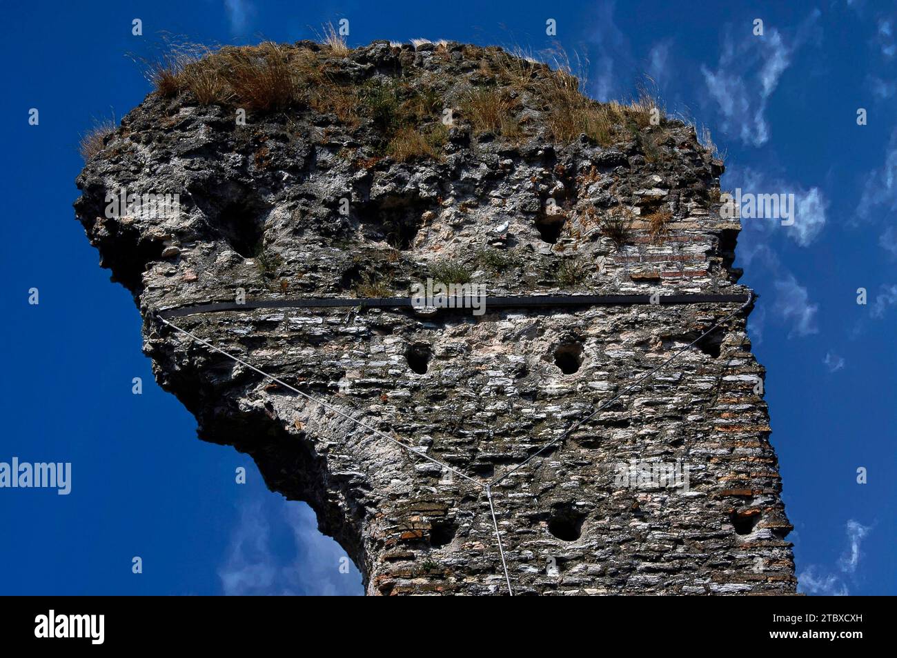 Der antike Turm ist mit einem Eisenband befestigt, das an einem Schlepper zwischen den Ruinen der Grotte di Catullo befestigt ist, einer römischen Villa in Sirmione auf der Halbinsel Sirmio, einer Landzunge am südlichen Ende des Gardasees in der Lombardei, Italien Stockfoto