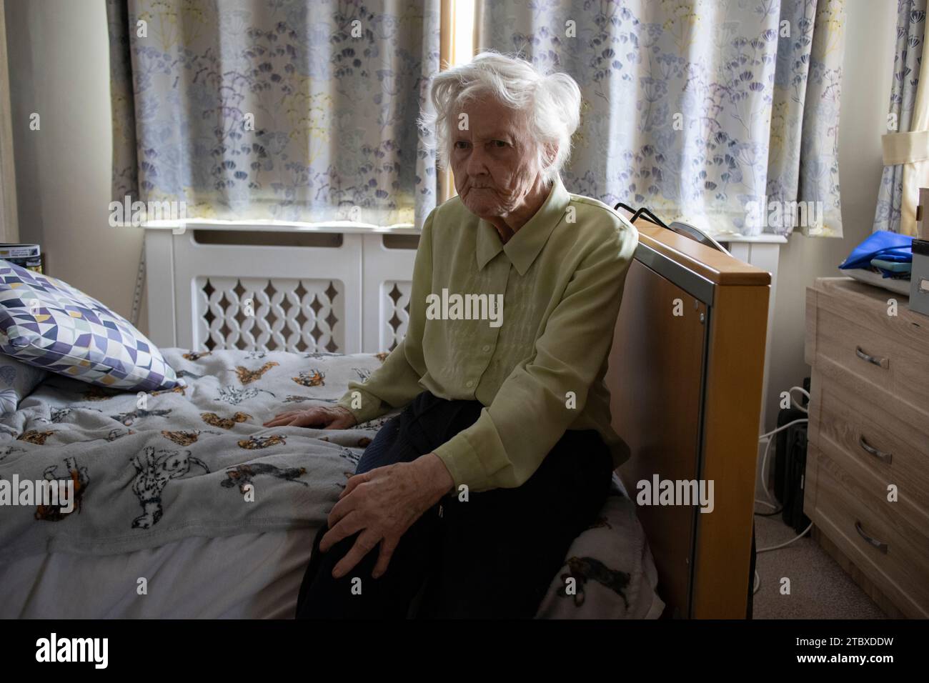 Eine ältere Dame in ihren 80ern sitzt allein in ihrem Schlafzimmer für Sozialfürsorge, England, Großbritannien Stockfoto