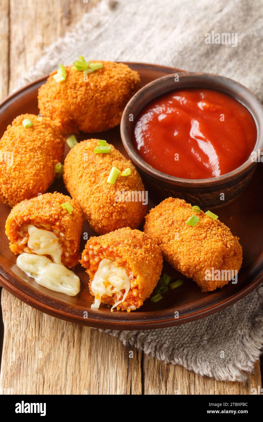 italienisches Fast Food gebratene Tomaten-Reis-Kroketten, gefüllt mit Mozzarella, auf dem Teller auf dem Tisch. Vertikal Stockfoto