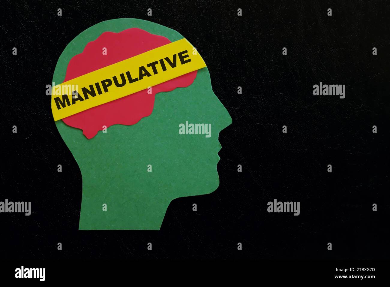 Menschliches Kopfprofil mit Wort manipulativ auf dunkelschwarzem Hintergrund. Manipulatives Verhaltenskonzept. Stockfoto