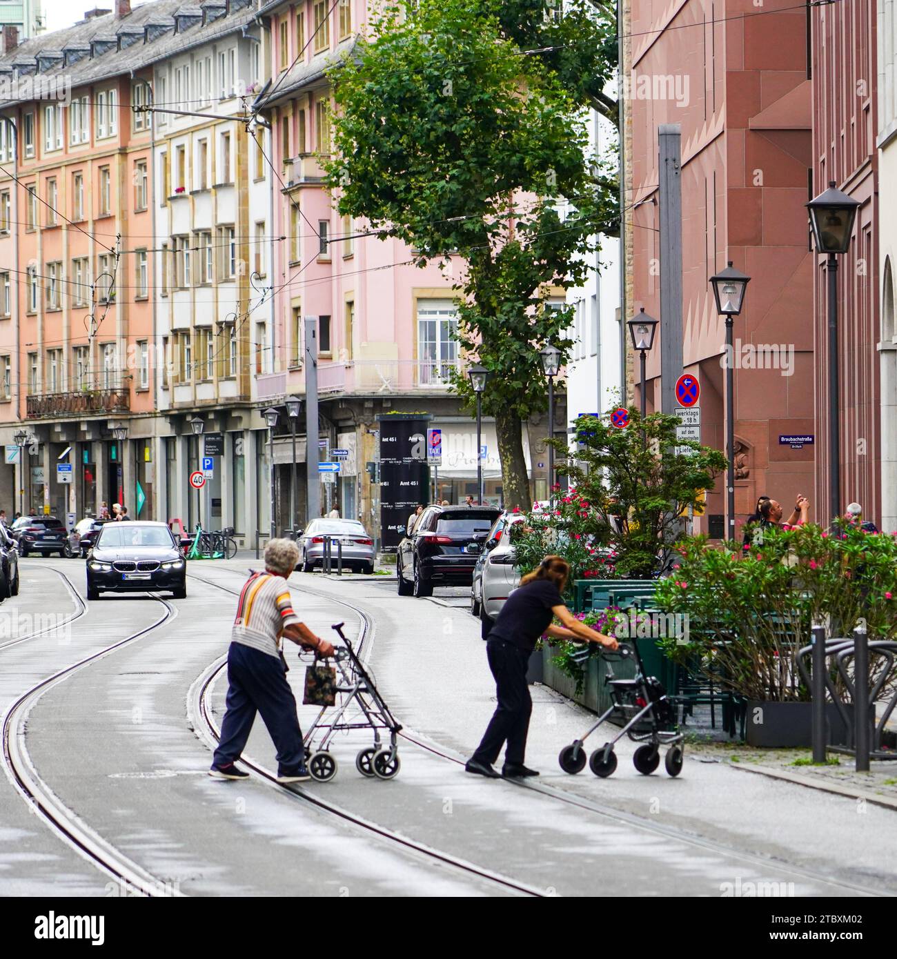 Zwei Seniorinnen mit Gehschwierigkeiten überqueren mit ihren Gehhilfen eine Straße. Stockfoto