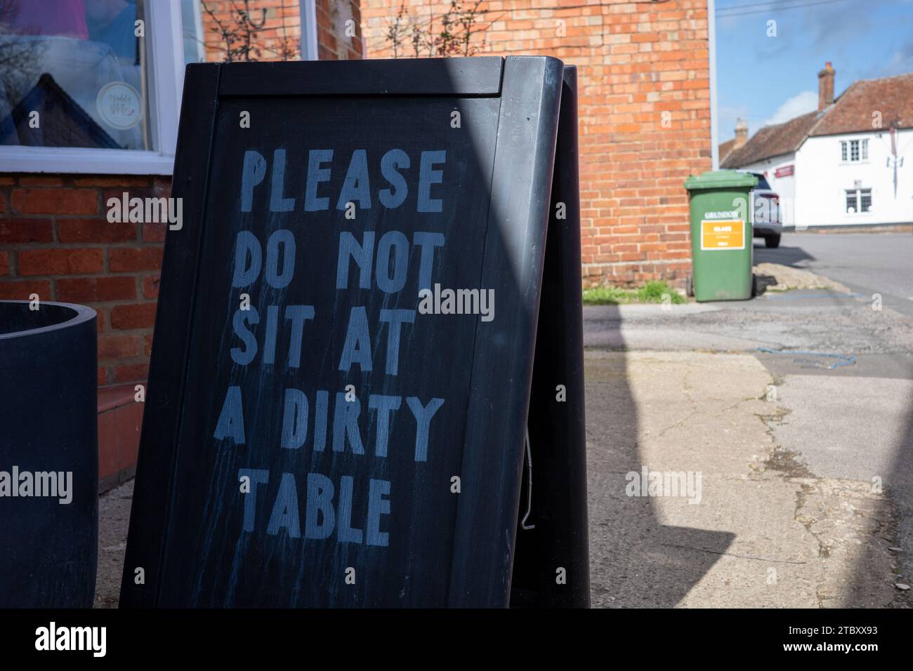 "Bitte setzen Sie sich nicht an einen schmutzigen Tisch." Straßenbrett Stockfoto