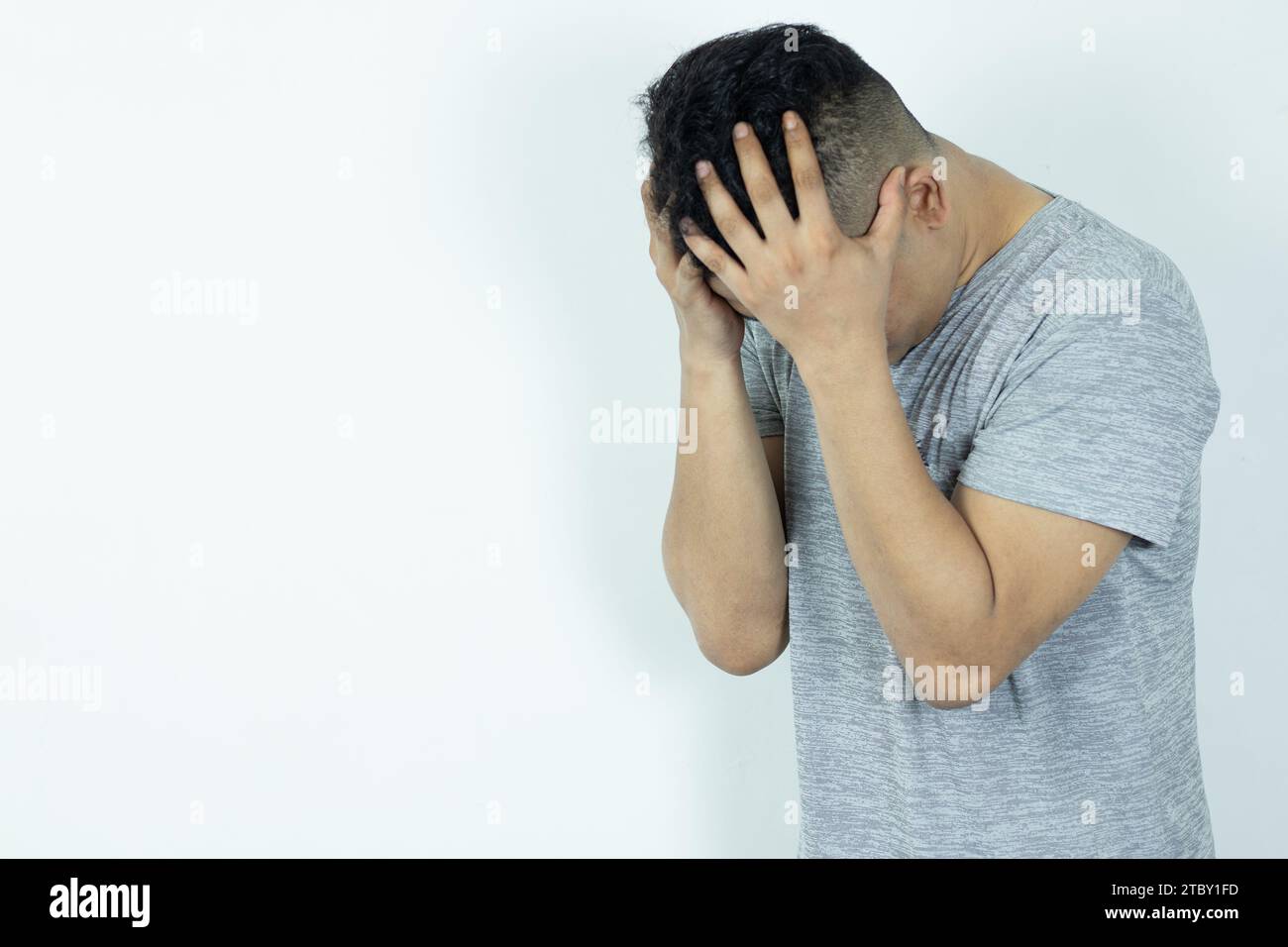 Porträt eines depressiven asiatischen Mannes, der sein Gesicht mit Händen versteckt. Gestresst, hoffnungslos, Frustration, psychische Störungen, Herzbruch und psychische Probleme. Stockfoto