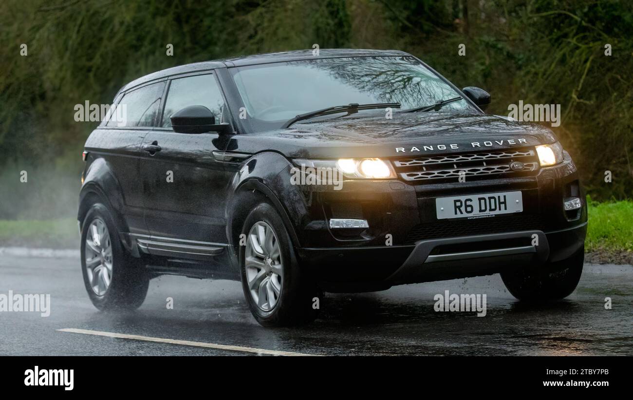 Milton Keynes, Bucks, Großbritannien - 9. Dezember 2023: 2014 Dieselmotor Range Rover Evoque Auto fährt auf nasser Straße, im Regen und bei eingeschalteten Scheinwerfern Stockfoto