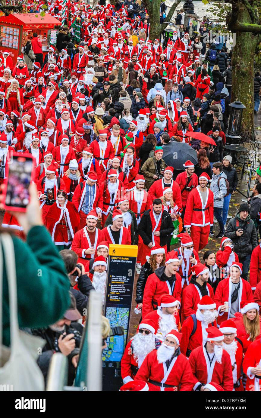 London, Großbritannien. Dezember 2023. Die santas spazieren und posieren entlang der South Bank und des Nationaltheaters. Hunderte von Teilnehmern in santa-Outfits haben Spaß bei der jährlichen SantaCon London Christmas Parade. Das Get Together, das gemeinnützig ist und auch für wohltätige Zwecke einsammelt, sieht die fröhlichen weihnachtsfeier einen Spaziergang von der Leake Street in Waterloo durch Teile Londons und endet am Abend am Trafalgar Square, wo sie verschiedene Pub-Haltestellen und Sehenswürdigkeiten entlang der Strecke besichtigen. Quelle: Imageplotter/Alamy Live News Stockfoto