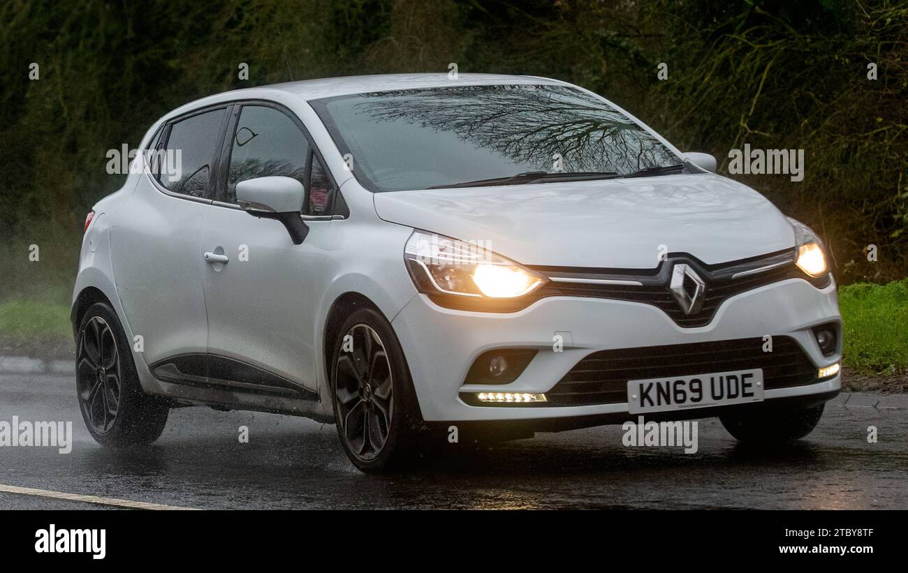 Milton Keynes, Bucks, UK - 13. Dezember 2023: 2019 weißes Renault Clio Auto fährt auf nasser Straße, im Regen und mit Scheinwerfern Stockfoto