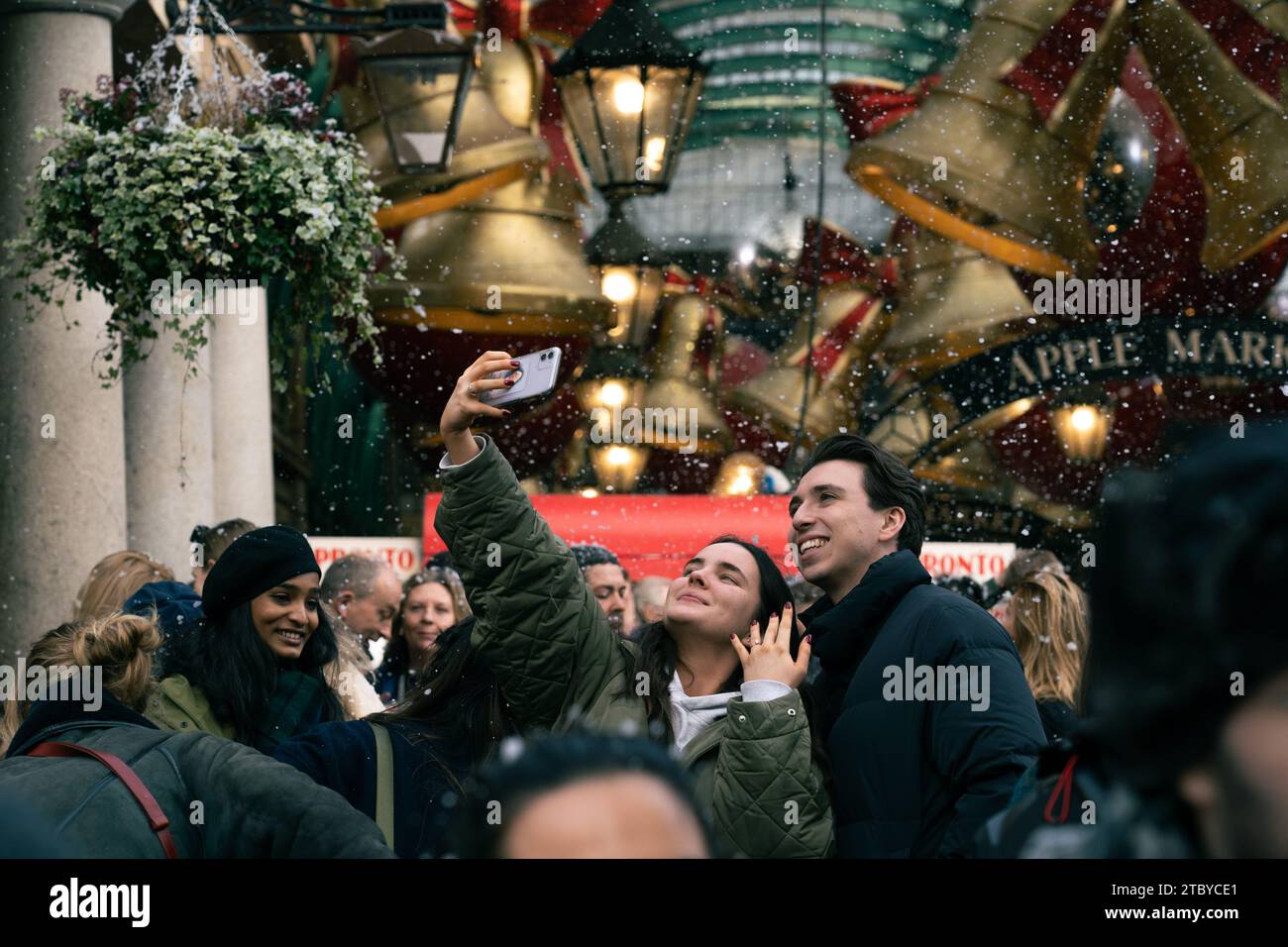 Leute, die den falschen Schneefall in London genießen, Covent Garden Stockfoto