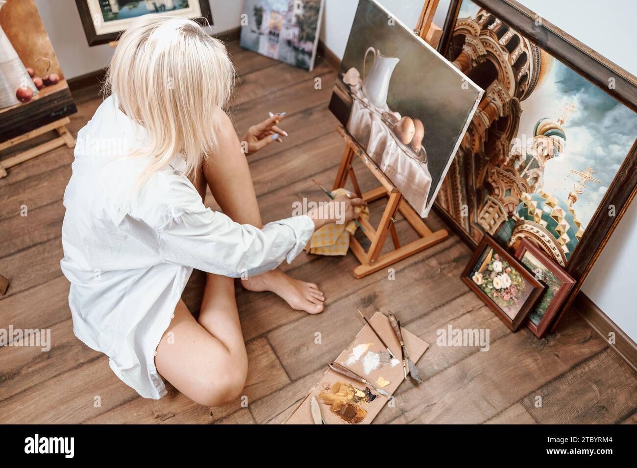 Eine junge, blonde Malerin, die ihr Kunstwerk zeigt Stockfoto