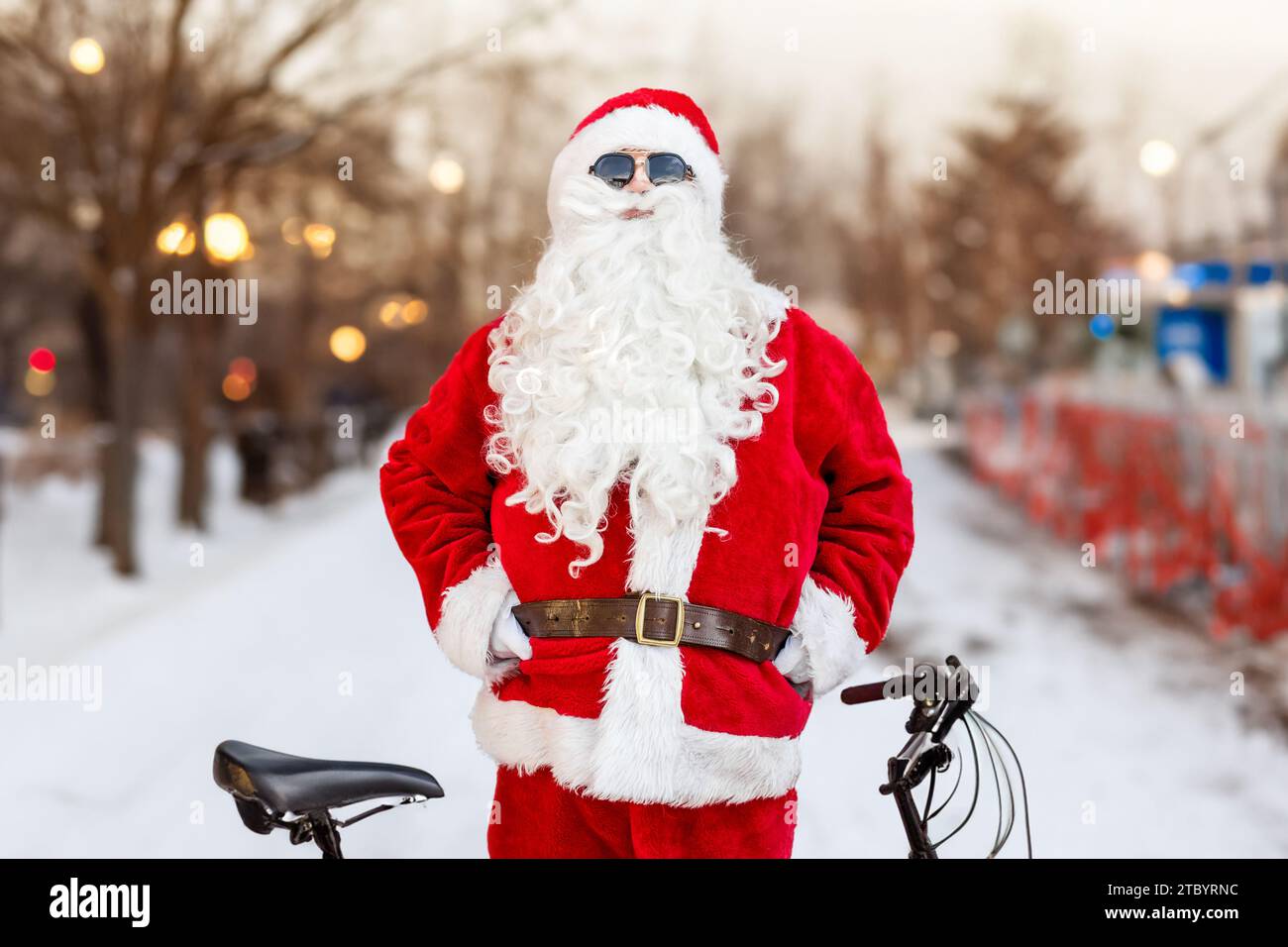 Der junge coole Weihnachtsmann steht mit seinem Fahrrad Stockfoto