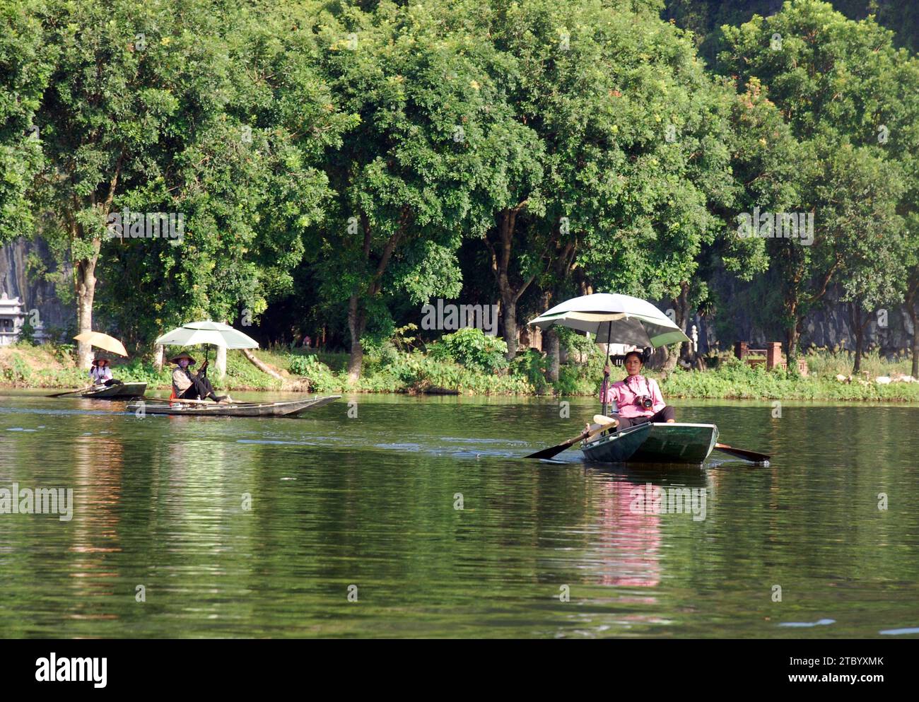 Lokale Fotografen nähern sich Touristenbooten auf dem Fluss bei Tam Coc in vietnam Stockfoto