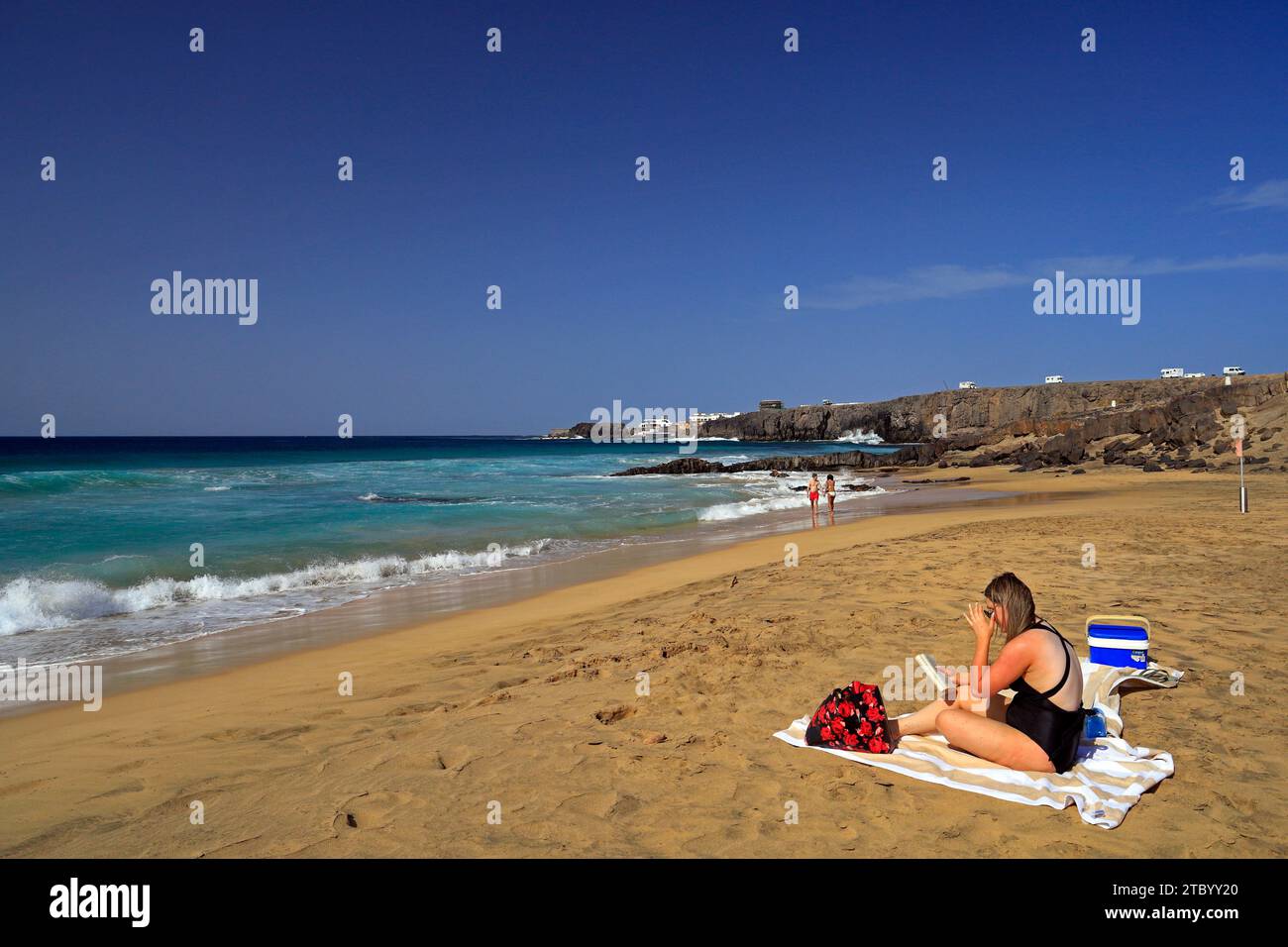 Frau, die sich mit einem Buch entspannt, Strand El Cotillo, Fuerteventura, Kanarische Inseln, Spanien. Vom November 2023 Stockfoto