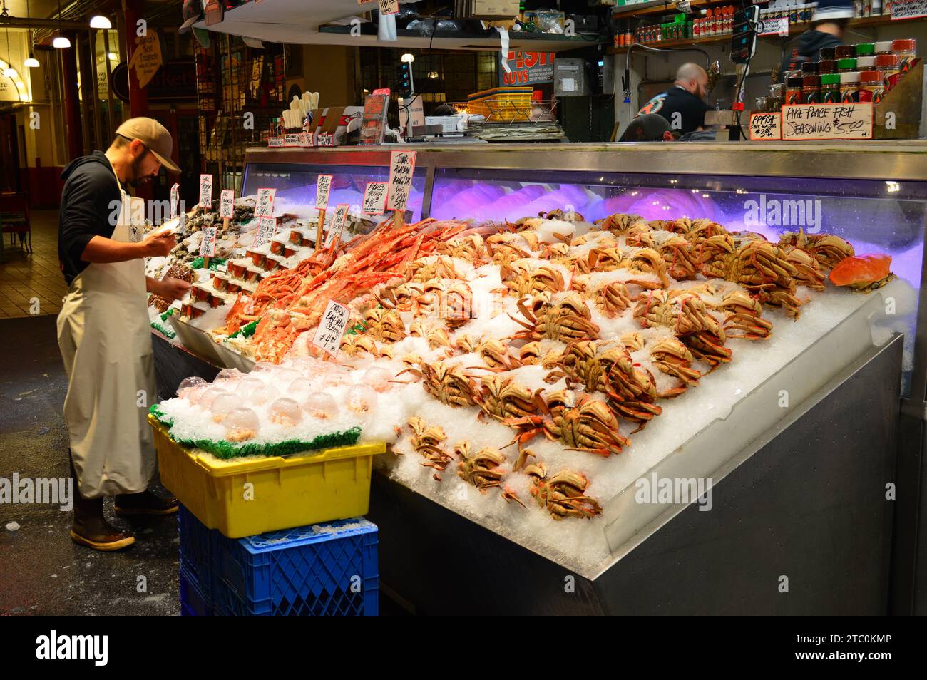 Ein Marktverkäufer untersucht den Fang von frischem Fisch und packt ihn auf dem Pike Place Market in Seattle in Eis Stockfoto