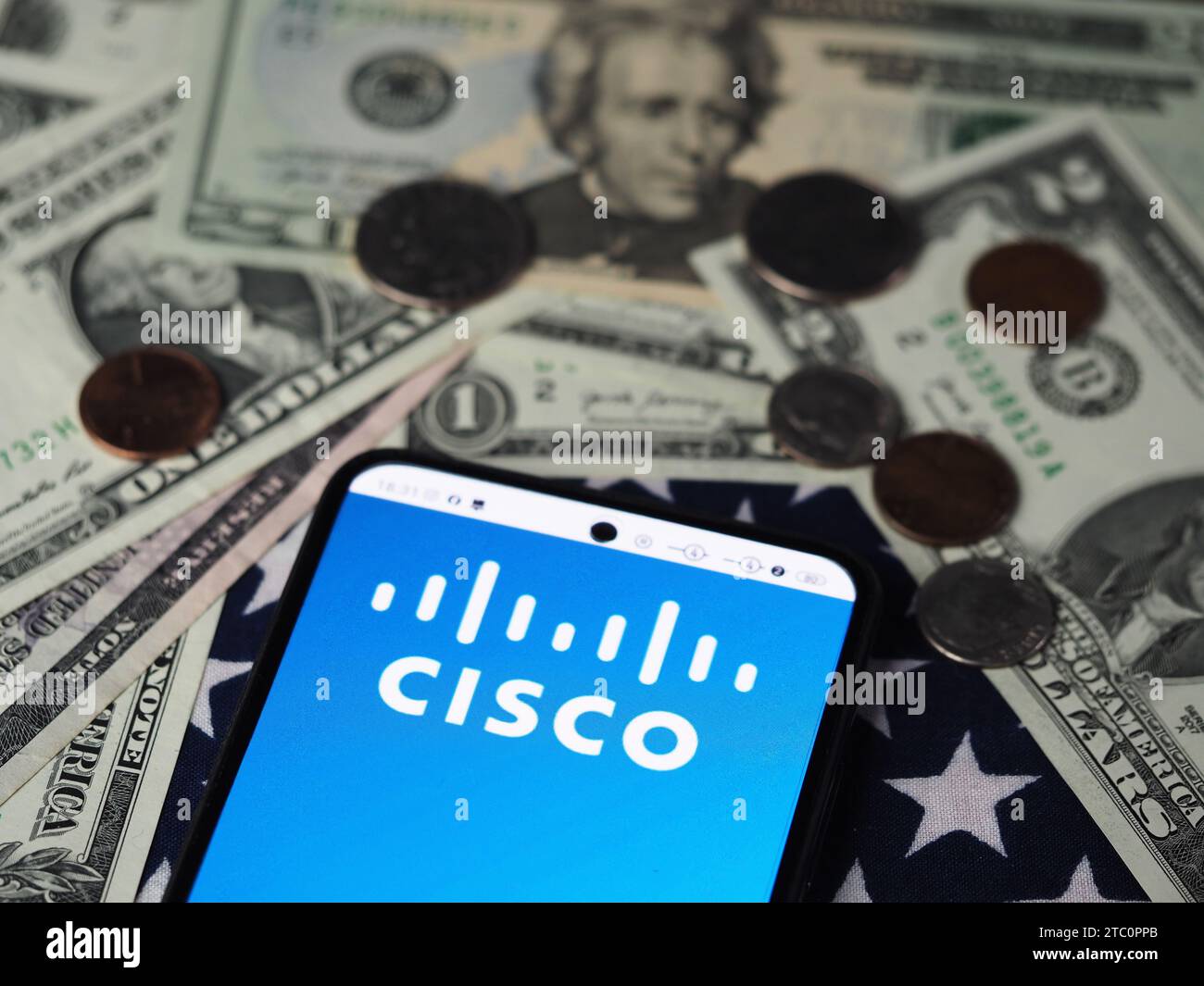 In dieser Fotoabbildung wird das Cisco Systems Logo auf einem Smartphone mit US-Dollar-Banknoten und -Münzen im Hintergrund angezeigt. Stockfoto