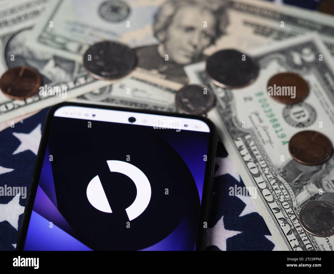 In dieser Fotoabbildung wird ein AppDynamics-Teil des Cisco-Logos auf einem Smartphone mit US-Dollar-Banknoten und -Münzen im Hintergrund angezeigt. Stockfoto