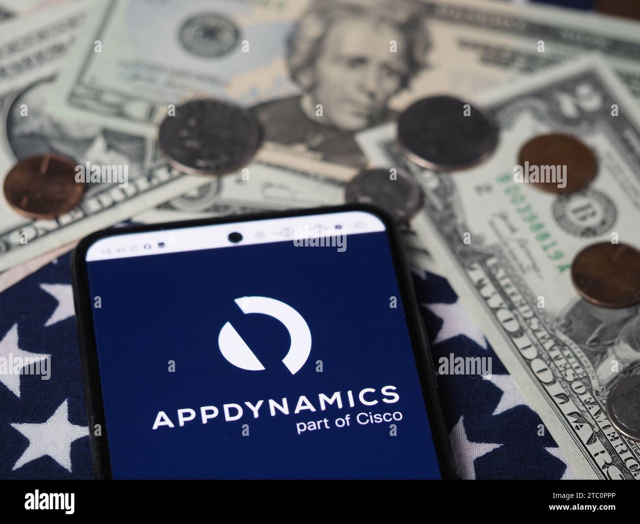 In dieser Fotoabbildung wird ein AppDynamics-Teil des Cisco-Logos auf einem Smartphone mit US-Dollar-Banknoten und -Münzen im Hintergrund angezeigt. Stockfoto