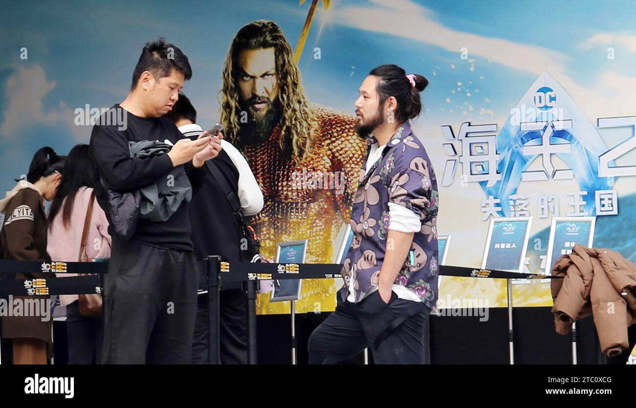 SHANGHAI, CHINA - 9. DEZEMBER 2023 - Fans vor einem Poster von Film Aquaman und das verlorene Königreich in einem Kino in Shanghai, China, 9. Dezember 2023. Stockfoto